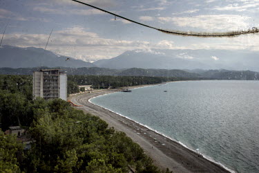 A view of the beach in Pitsunda with mountains in the background seen through a broken window pane.