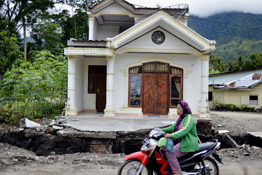 A woman rides a scooter past a house on Samosir Island. The island is surrounded by the 5000km2  Lake Toba that formed in the crater of an extinct super volcano. The region is also home to the Toba Ba...