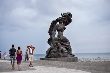 People walk past a Soviet era statue on the beach in Pitsunda.