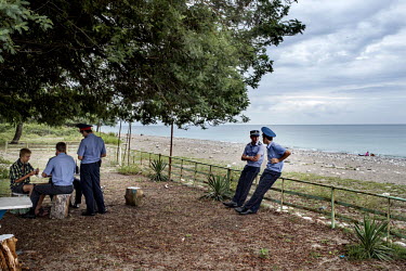 Policemen chat and play cards with a boy near the beach in Sukhumi.