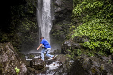 A man jumps across rocks below a waterfall near the former mining town of Tkvarcheli.