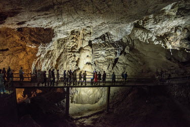 Tourist walk across a walkway inside the Novi Afon cave, past the rock formation known as 'The Skeleton'.
