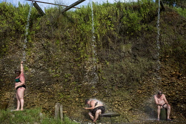 People sit under streams of hot water pouring out of pipes at the Kyndyg thermal springs.