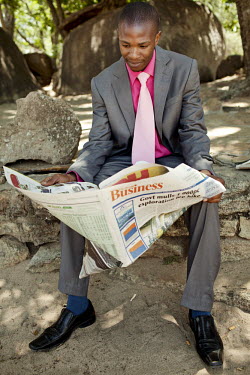 A man in a suit reading the business section of a newspaper.