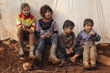 Children sit in front of a makeshift shelter in a refugee camp for Syrian refugees in the Bekaa (Beqaa) Valley in Lebanon. Since the beginning of the civil war in Syria, some 880,000 Syrians have fled...