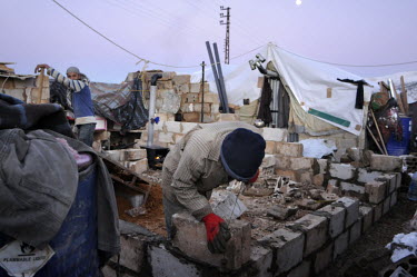 A man builds a shelter out of breeze blocks in a refugee camp for Syrian refugees in the Bekaa (Beqaa) Valley in Lebanon. Since the beginning of the civil war in Syria, some 880,000 Syrians have fled...