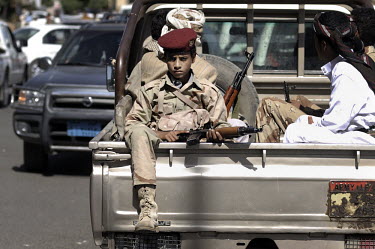 A child soldier, defected from the government's side, sits in the back of a truck on 60th street at a funeral for 12 protestors killed by pro-President Salah troops during recent anti-government prote...