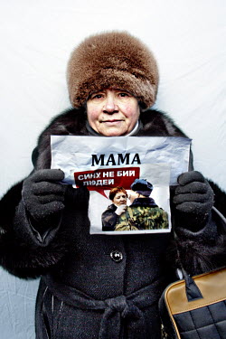 A woman holding a piece of paper which shows a woman speaking to a soldier and reads: 'Son, don't beat the people.' poses for a portrait during an anti government protest in central Kiev.  Tamara (64)...