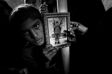 A youth holds the portrait of a gun toting militant, killed during an Israeli raid, at their funeral.