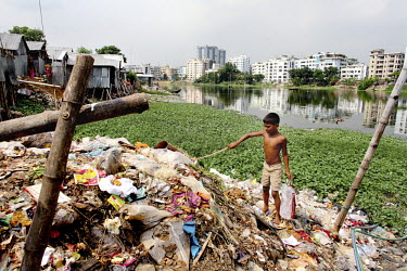 A boy picks through a pile of rubbish searching for recyclable materials in the Korail Slum.