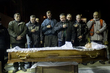 People pay their respects to a dead protester whose coffin is borne on a wooden box at the funeral of  one of the dozens of protesters who died in clashes between Police and protesters in Kiev. Protes...