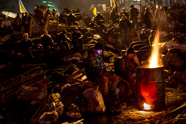 A protester checks his phone in a group of protesters sitting around a fire burning in an oil drum on Maidan Nezalezhnosti (Independence Square), renamed EuroMaidan by protesters since November 2013....