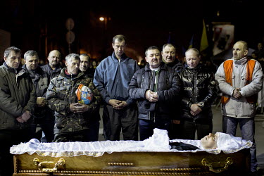 Men stand beside the coffin of one of the dozens of protesters who died in clashes with police in Kiev. Protests against the government of President Viktor Yanukovych were sparked on 21 November 2013...