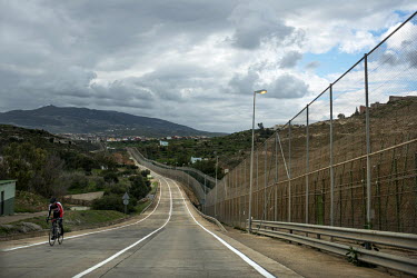 A cyclist rides a road that runs beside the border fence separating the Spanish exclave of Melilla and Morocco. Melilla is a Spanish city on the north coast of Africa, bounded by Morocco and the Medit...