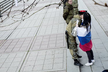 A woman draped in a Russia flag kisses an armed man who is part of a militia surrounding the regional parliament in Simferpol while it deliberates on a referendum to be held to decide the future of Cr...