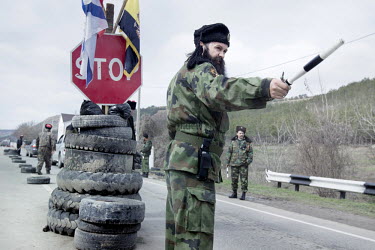 A militiaman wearing the insignia of Russian Cossacks on his fur cap mans a roadblock the town of Verkhn'osadove. The pro Russian militia have set up roadblocks to control movement around Crimea.   Si...