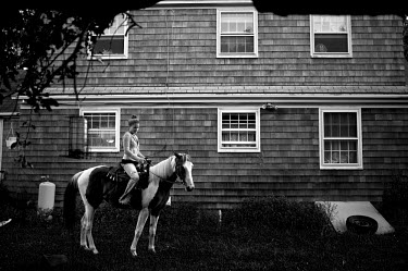 Katie sits on her horse outside her grandfather's house.