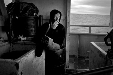 Deck-hand Kenny smokes a cigarette at the back of the a commercial swordfish trawler. There are conflicting arguments as to the health of the North Atlantic Broadbill swordfish (Xiphias gladius) popul...