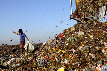 A boy looks for recyclable material next to an earth mover at the biggest rubbish dump in Dhaka. The city alone generates about 3500 to 4000 metric tons of solid waste each day.