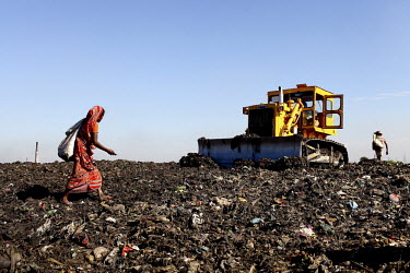A young woman passes a bulldozer as she looks for recyclable material at the biggest rubbish dump in Dhaka. The city alone generates about 3500 to 4000 metric tons of solid waste each day.