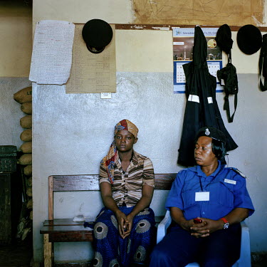 Isatu Sesay (18) sits beside a police officer at the Makeni central police station where she has been held without charge for two months on suspician of murdering a child in her care.