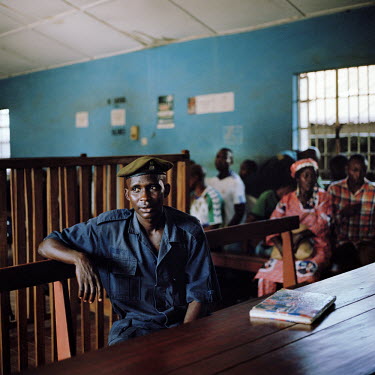 A prison guard sits at the prosecutor's table during a recess of the magistrate's court.
