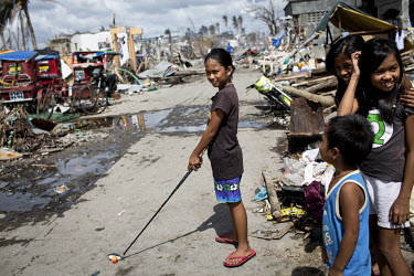 A girl prepares to hit a golf shot while playing with friends among the devastation in Tacloban after Typhoon Haiyan swept through the Philippines. Typhoon Haiyan, or Yolanda as it is known in the Phi...
