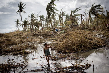 A young girl wades through water near her destroyed home, near Tacloban. Typhoon Haiyan, or Yolanda as it is known in the Philippines, made landfall on 8 November 2013 and was one of the deadliest typ...