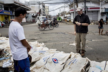 A pastor administers the last rights to bodies laid out for collection on a street corner in Tacloban after Typhoon Haiyan swept through the Philippines. Typhoon Haiyan, or Yolanda as it is known in t...