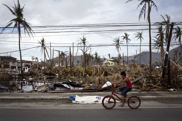 A boy cycles past a dead body in Tacloban city after Typhoon Haiyan swept through the Philippines. Typhoon Haiyan, or Yolanda as it is known in the Philippines, made landfall on 8 November 2013 and wa...