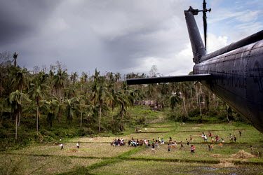 A group of people run to collect humanitarian aid, including rice and water, dropped by a Philippines Air Force helicopter in a village in a remote part of Leyte Island. Typhoon Haiyan, or Yolanda as...