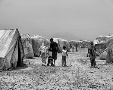A family walking between two rows of tents in Kharaz refugee camp. The camp holds roughly 15,000 mostly Somali migrants, half of whom are children. The United Nations Refugee Agency (UNHCR) has raised...