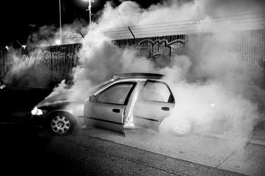 Smoke pours from a car that has been pushed too hard by its driver at a 7th Street Sideshow, an illegal gathering of car and motorbike enthusiasts who come together to perform stunts and hold street d...