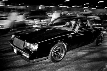 Two men ride in a vintage car during a 7th Street Sideshow, an illegal gathering of car and motorbike enthusiasts who come together to perform stunts and hold street drag races. In the Bay Area, deep...