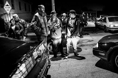 Onlookers during a 7th Street Sideshow, an illegal gathering of car and motorbike enthusiasts who come together to perform stunts and hold street drag races. In the Bay Area, deep in East Oakland, bac...