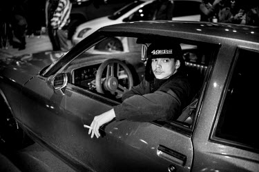 A man sits in his car during a 7th Street Sideshow, an illegal gathering of car and motorbike enthusiasts who come together to perform stunts and hold street drag races. In the Bay Area, deep in East...