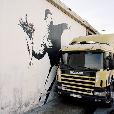 A truck parked beside a mural by British street artist Banksy painted on the side of a petrol station.
