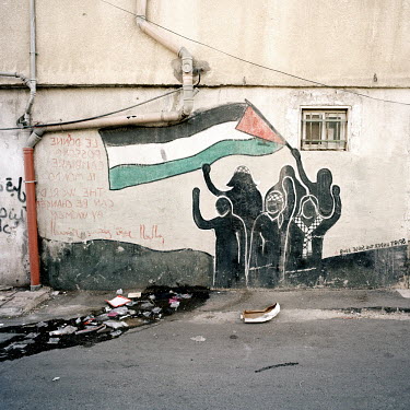 A mural of a group of people waving a Palestinian flag.