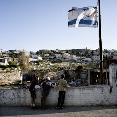 Settler's children stand beneath an Israeli flag.