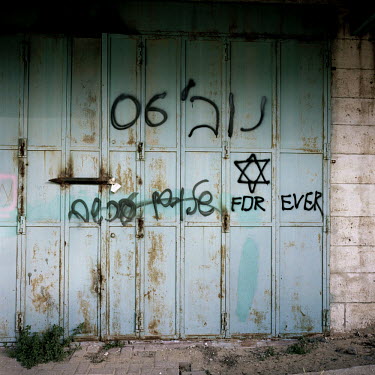 Closed Arab shops, defaced with Hebrew graffiti, on Shuhada Street.
