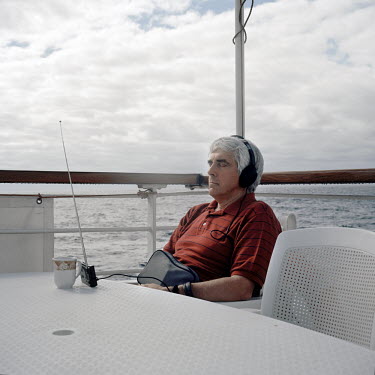 A passenger listens to a radio on the deck of the RMS St Helena. There are only two remaining Royal Mail Ships, the other being Cunard's Queen Mary 2. The RMS St Helena is the only link to the outside...