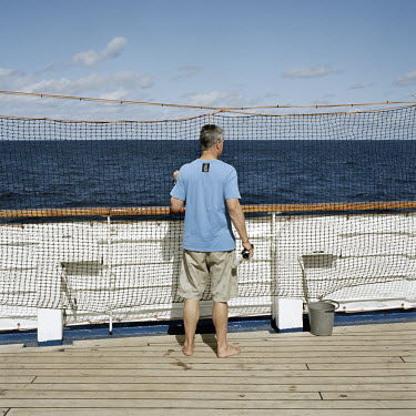 A tourist on deck on the RMS St Helena looks out to sea. There are only two remaining Royal Mail Ships, the other being Cunard's Queen Mary 2. The RMS St Helena is the only link to the outside world f...