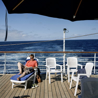 A passenger reads a book on the deck of the RMS St Helena. There are only two remaining Royal Mail Ships, the other being Cunard's Queen Mary 2. The RMS St Helena is the only link to the outside world...