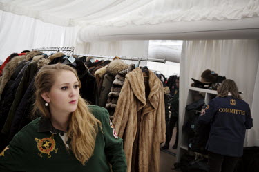 A volunteer from a local finishing school attends the VIP cloakroom tent at the 30th Polo on Snow World Cup. Racks of fur coats attest to the wealth of the guests attending the event.