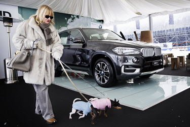 Mariella Broggini (62) and her pet chihuahuas, Valentino and Charlotte, pass by a luxury display vehicle in the BMW marquee. The German car manufacturer are a sponsor of the 30th Polo on Snow World Cu...
