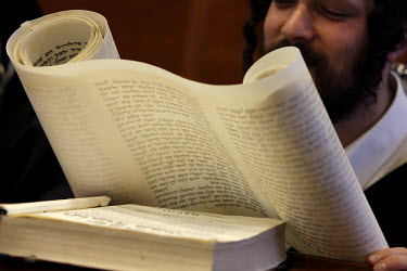 An Orthodox Jew reads from the Book of Esther scrolls during a Purim celebration in the Belz Synagogue.