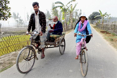 Info Lady Jeyasmin rides her bicycle past a cycle rickshaw on a country road. In rural Bangladesh the Info Ladies are bringing internet services to men and women who need information but don’t have...