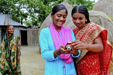 18 year old Munira checks a photograph taken by Info Lady Mahfuza. Her husband of ten months works in far of Dhaka and wanted a picture of his wife to carry with him. In rural Bangladesh the Info Ladi...