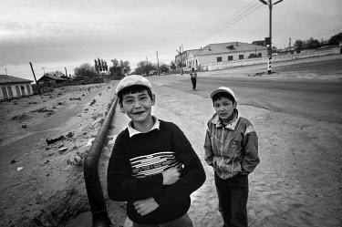 Two young boys standing in the sand at teh side of  a road. During the 1950s and the 1960s the rivers that feed the Aral Sea (the Amu Darya and the Syr Darya) were diverted for irrigating cotton and o...