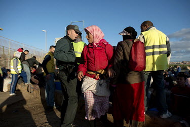 Nora El-KouKhou (centre wearing as red jacket) is stopped by a Spanish border policeman as she tries to be first in line to cross the Moroccan-Spanish border. Hundreds of people work ferrying heavy lo...